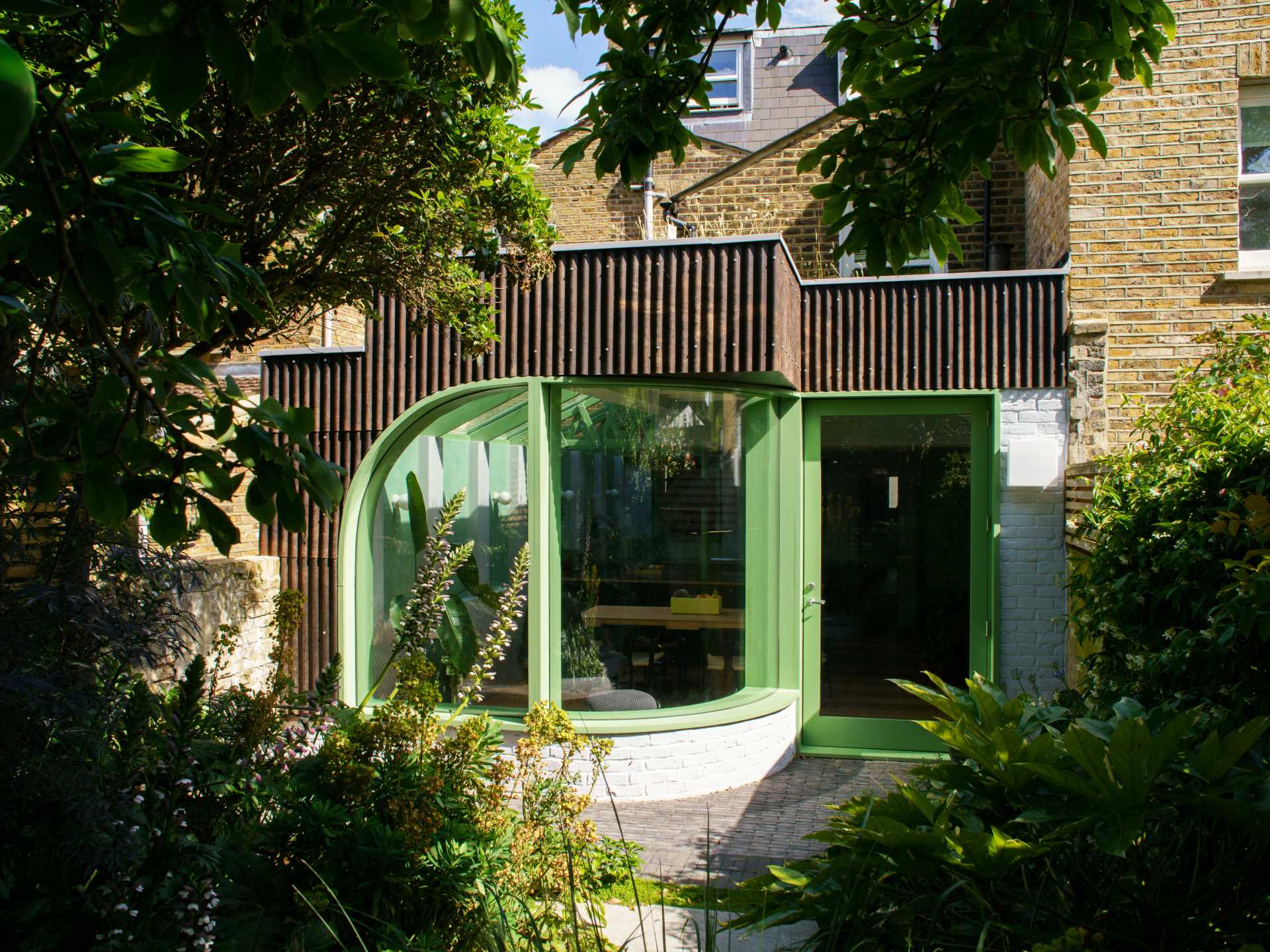 A modern home extension with a curved window, a skylight, and a new dining area and custom kitchen with IKEA cabinets.