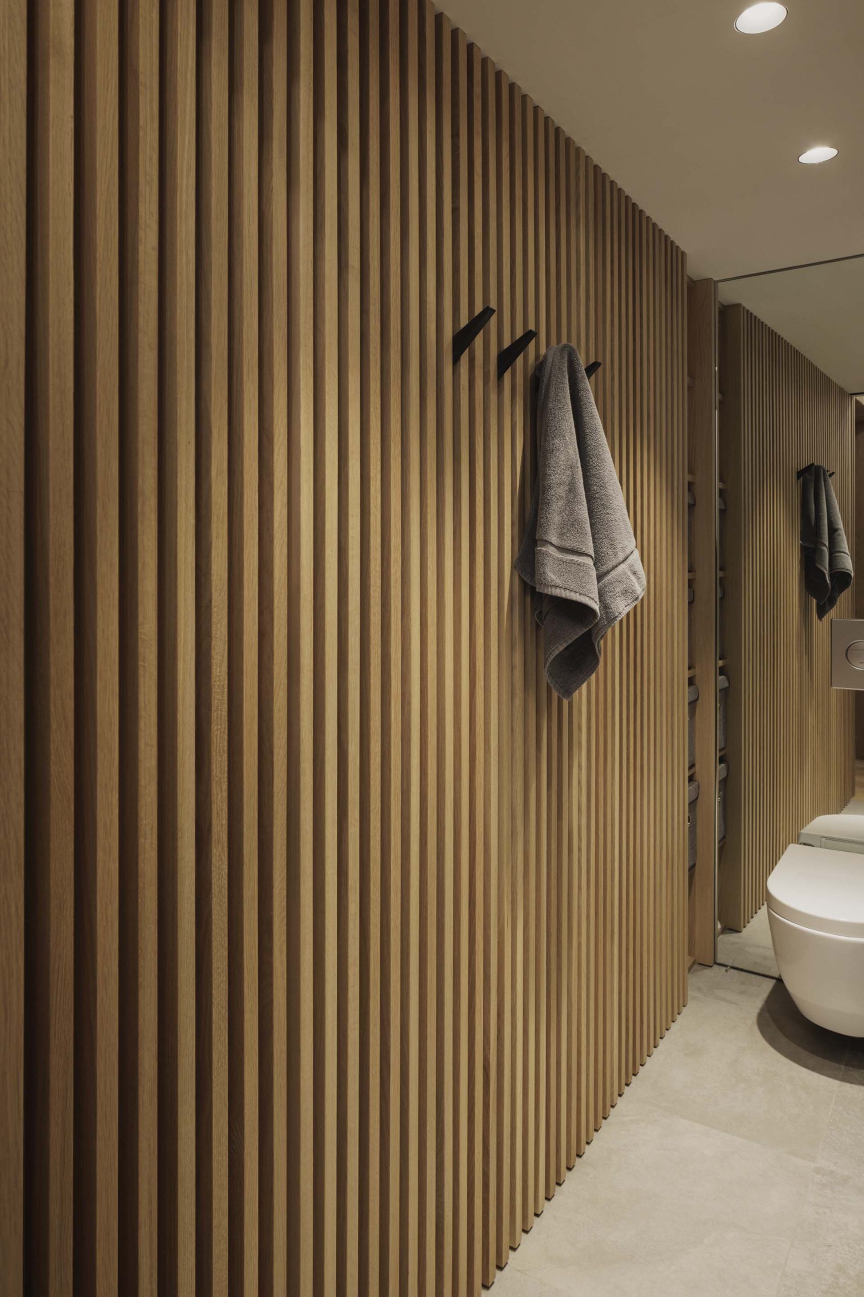 The slat wall continues in the bathroom, where it's been paired with striated slate gray and glass.