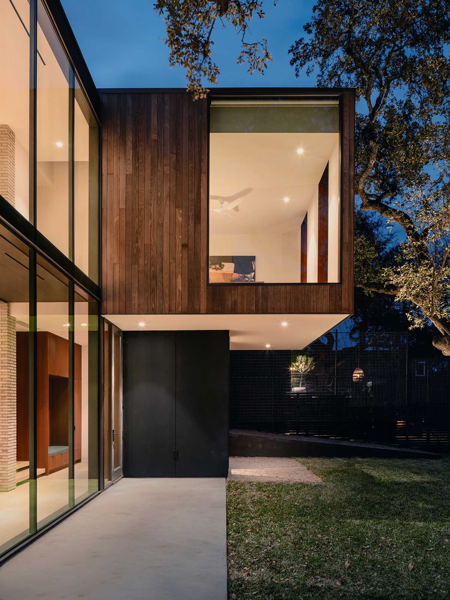 The exterior of the home features concrete, wood, and large windows, with some parts of the house extending out over the ground below.