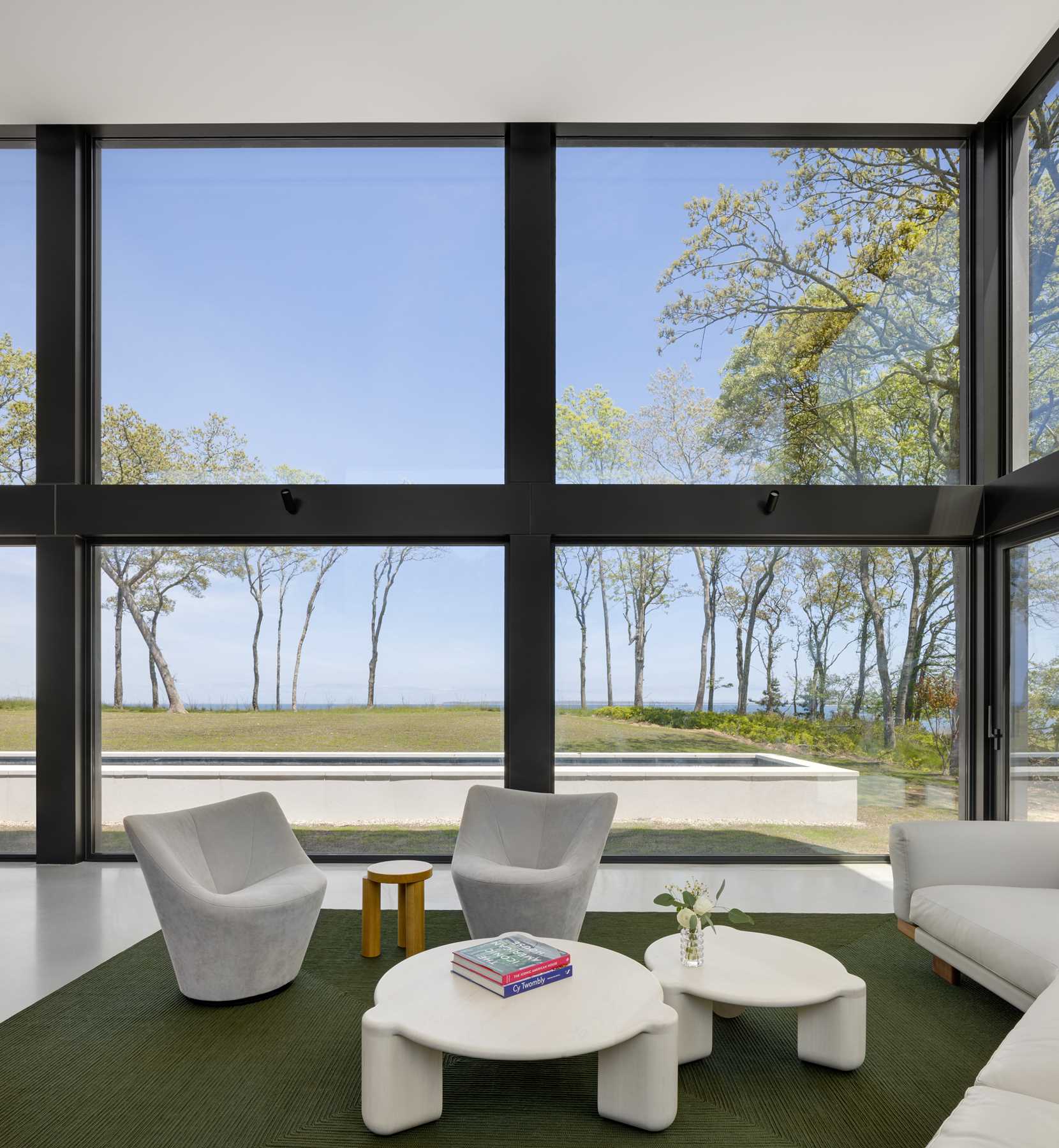 A modern living room with a double-height ceiling and thick black frames.