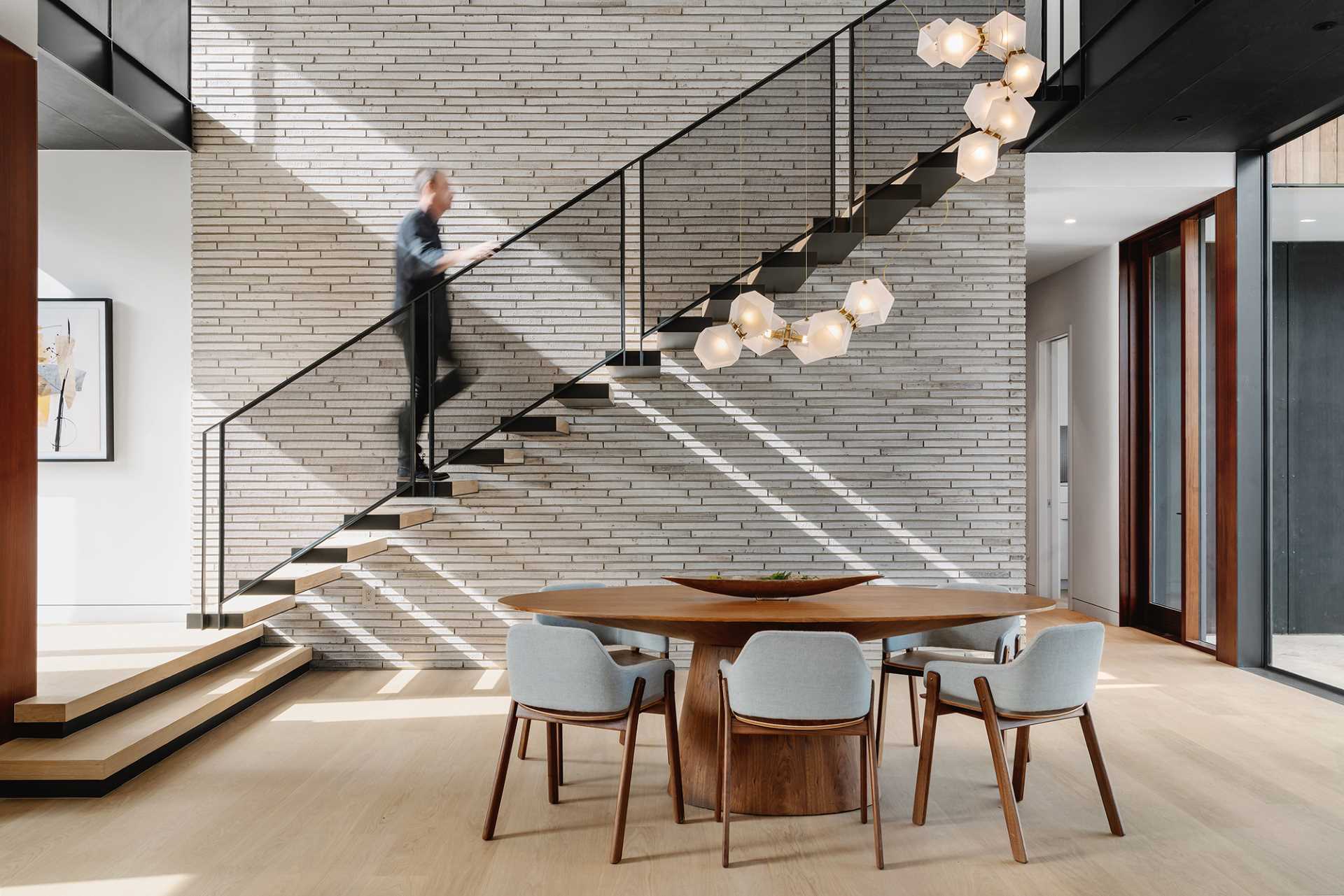 An open plan dining area is anchored in the space by a delicate and sculptural light fixture.